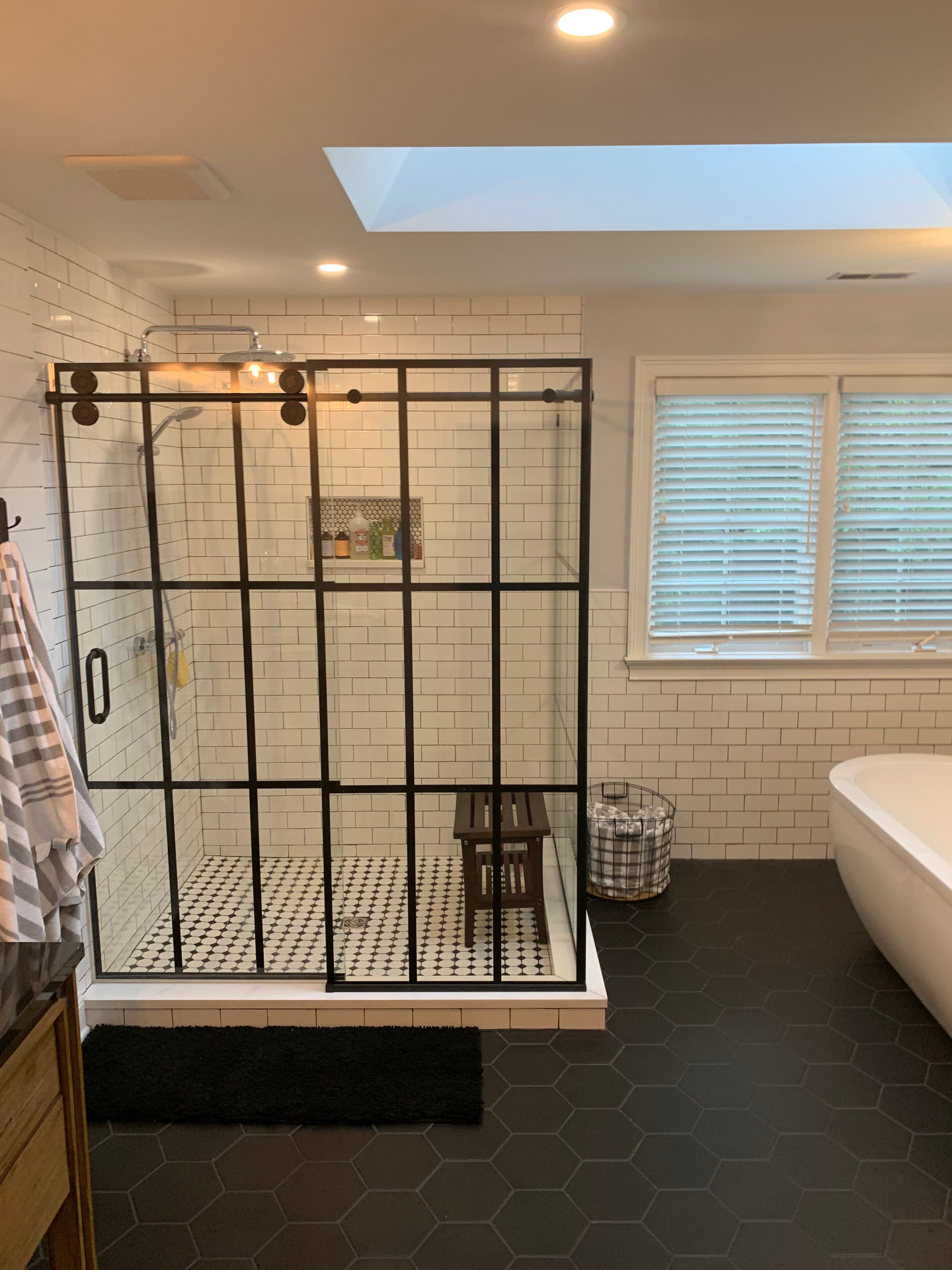 Completed primary bathroom with matte black shower enclosure and soaking tub